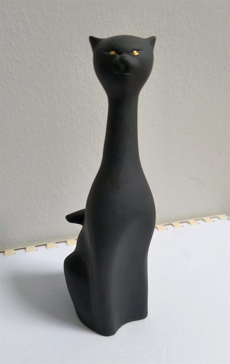 Fekete, matt mázas, megnyújtott testű porcelán macskafigura aranyszínű szemekkel.